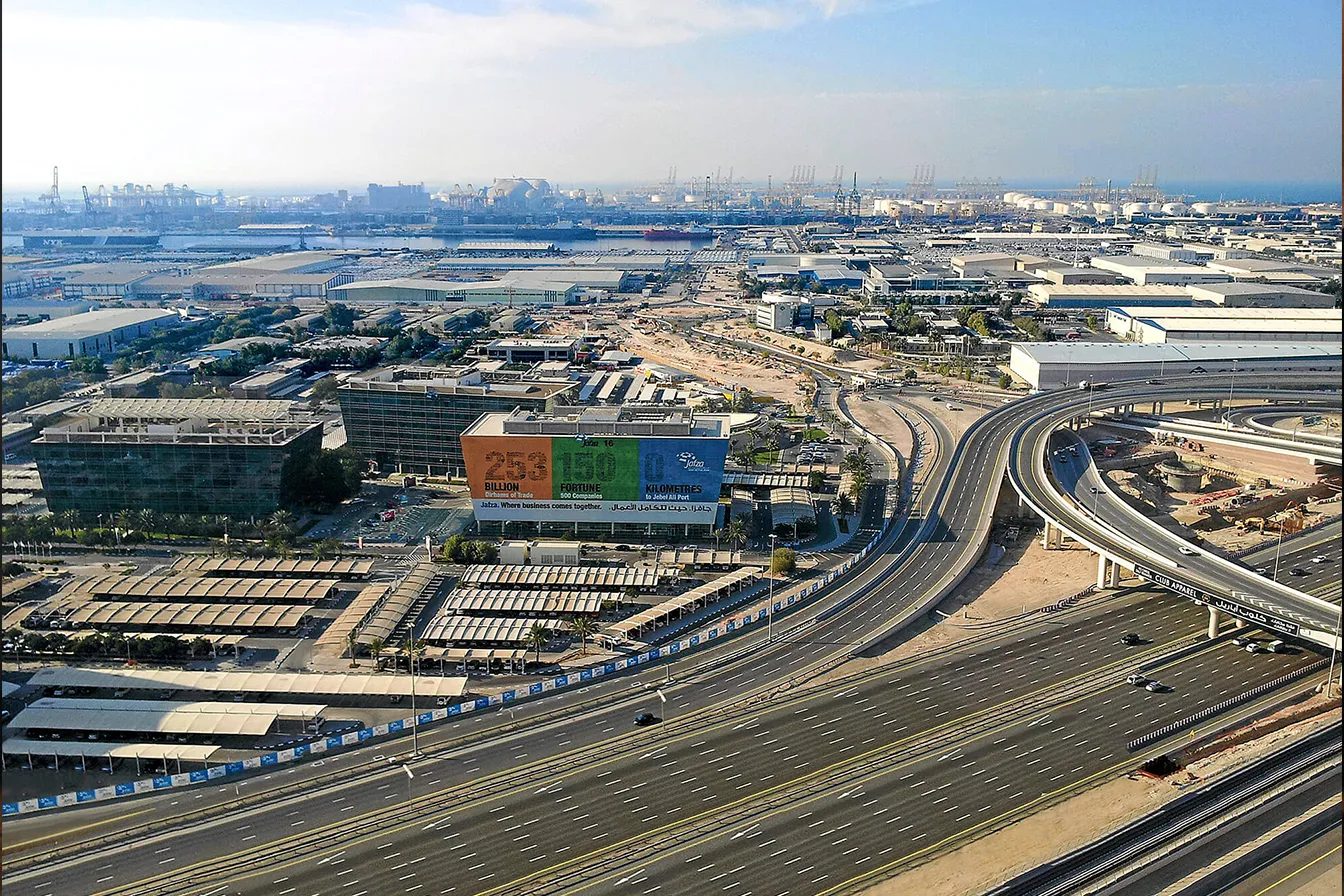 صورة تجمع بين رافعات ميناء جبل علي ومجمع سكني حديث في الخلفية